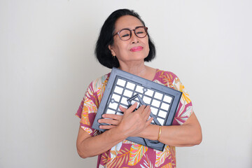 Wall Mural - Asian elderly woman hugging her family photo showing longing expression