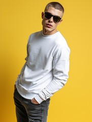 Wall Mural - Portrait of handsome man with sunglasses wearing white Sweatshirt and dark grey jeans with short hairstyle cut isolated on yellow background