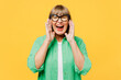 Elderly blonde woman 50s years old wears green shirt glasses casual clothes scream sharing hot news about sales discount with hands near mouth isolated on plain yellow background. Lifestyle concept.