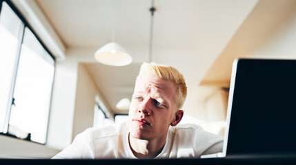 Focused Young Man Using Laptop in Bright Room