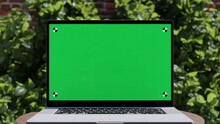 Laptop With Green Screen, Close-up Slow Motion Animation, Outdoor Scene With Brick Wall And Green Leaves And A Wooden Desk, 4k