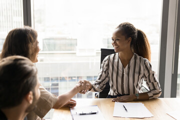 Poster - Happy confident African American businesswoman giving handshake to manager, reaching successful agreement, discussing cooperation, business partnership, contract on group meeting