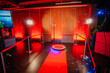 © Raivo - 360 spinner photo booth setup with a red carpet and lighting in a venue with red ambient lighting...