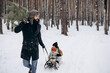 © Ananass - a happy father is sledding his children in the middle of a pine forest with a Christmas tree that they chose together and cut down for Christmas