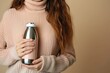 © LimeSky - Closeup of woman with thermos bottle on beige background