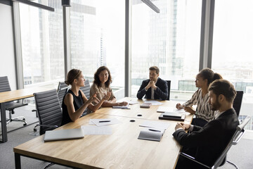 Wall Mural - Multiethnic team of partners discussing deal, agreement, partnership in modern city office interior. Diverse business colleagues talking on project strategy, brainstorming on new ideas on meeting