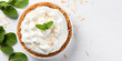 Top view of coconut cream pie garnished with mint leaves on white background with copy space Delicious fresh baked healthy dessert