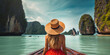 © red_orange_stock - Back view of a woman in a straw hat looking out at a stunning ocean view with limestone cliffs while on a boat trip.