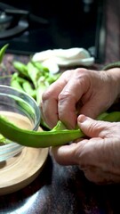 Wall Mural -  Slow motion,shelling tender green beans into a glass bowl.