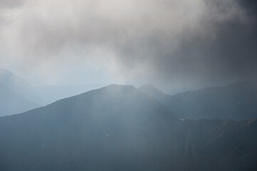 Fototapeta chmury otaczające górskie szczyty.