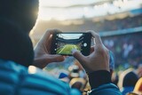 Fototapeta  - A hand with a smart phone in a stadium, during a sports event