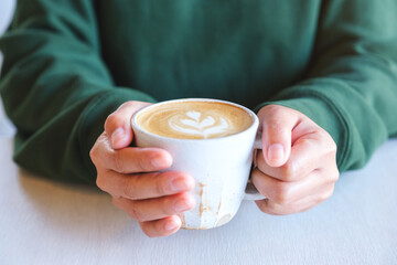 Closeup image of a woman holding a cup of latte coffee