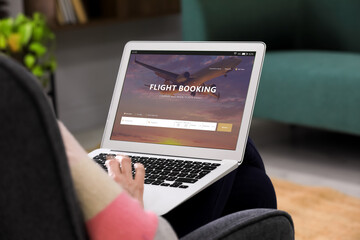 Wall Mural - Man using laptop to book flight at home, closeup