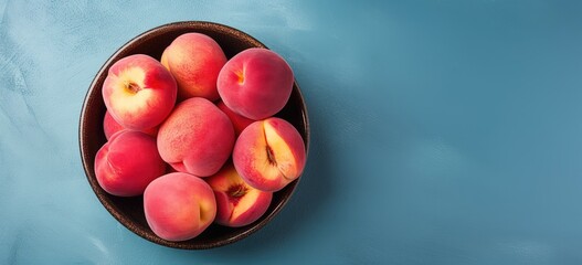 Wall Mural - Fresh apricot or peach in bowl on blue textured background. Creative food concept. Vegan, vegetarian. Peach fuzz color. Flat lay, top view with copy space