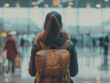 Girl / Woman With A Backpack And Winter Jacket Seen From Behind, Waiting At An Airport Boarding Gate Or Train Station	