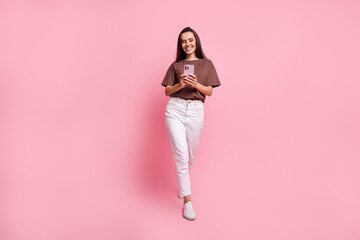 Sticker - Full body length photo of young successful businesswoman brunette hair smm manager busy steps with phone isolated on pink color background