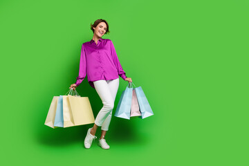 Wall Mural - Full length photo of lovely adorable girl hold packages new fashion collection clothes empty space isolated on green color background