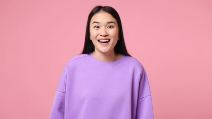 Wall Mural - Young fun woman of Asian ethnicity wear purple sweatshirt look around for friend find waving meet greet with hand as notices someone say hello hi isolated on plain pastel light pink background studio