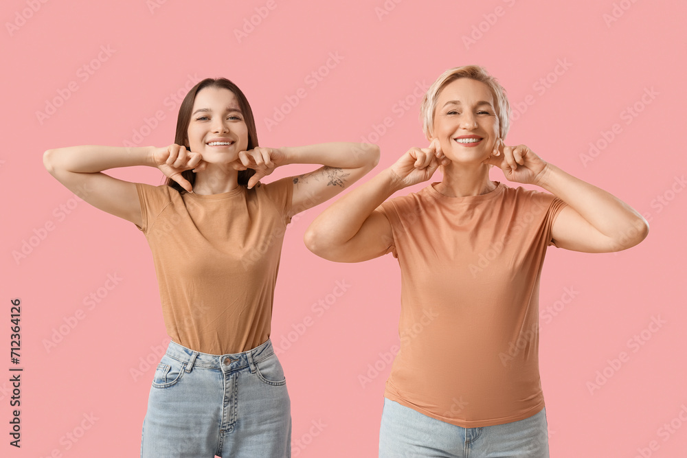 Beautiful women doing face building exercise on pink background