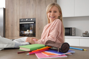 Poster - Little schoolgirl unpacking backpack in kitchen