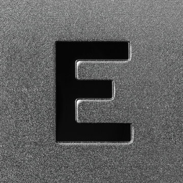 Letter E on a silver grained shiny metal surface. English alphabet.