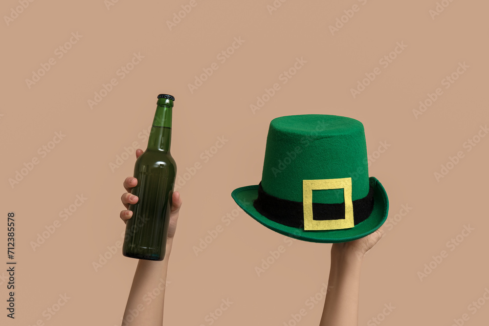 Hands with beer and leprechaun's hat on beige background. St. Patrick's Day celebration