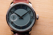 Gents Wrist Watch With Green Clock Face Lays On A Wooden Table