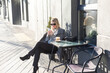 © Angelov - Portrait of tanned lady with cup of latte on foreground. Smiling woman in sunglasses during breakfast in cafe.