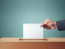 Close-up Of A Man's Hand Putting A Voting Sheet Into A Cardboard Ballot Box On A Blue Background.