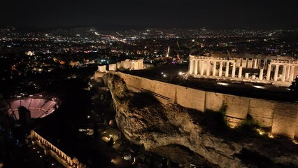 Wall Mural - Aerial drone night cinematic video of iconic illuminated landmark Acropolis hill and the Masterpiece of Ancient times and Western civilisation - the Parthenon, Athens, Attica, Greece