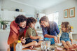 © Marko Geber - Family baking together in the kitchen with children making a mess