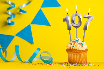 Birthday candle number 107 with cupcake - Yellow background with blue pennants