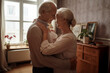 © Richard - Happy elderly old couple in living room holding each other generative ai