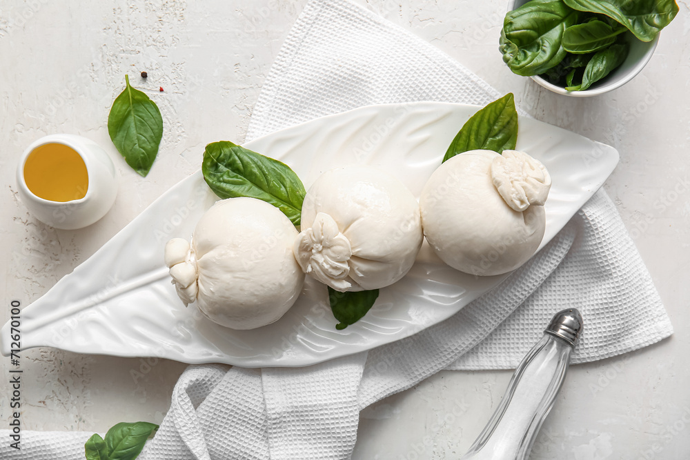 Plate of tasty Burrata cheese with basil on white background