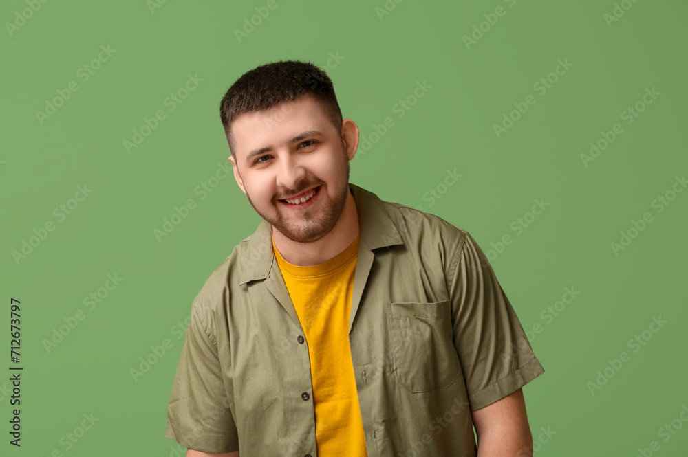 Handsome happy young man laughing on green background