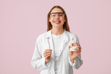 Sticker - Female dentist with jaw model and dental mirror on pink background. World Dentist Day