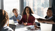 © fizkes - Presenting idea. Inspired black african woman employee propose marketing plan to interested diverse colleagues on briefing. Young biracial female manager expert talk to teammates express point of view