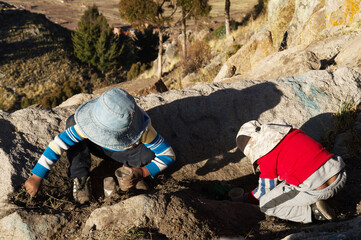 Two children playing with dirt on top of a hill