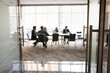 © fizkes - Group of businesspeople sitting at large conference table in negotiation room. Project partners brainstorming on ideas, discussing collaboration terms, teamwork. Business meeting blurred background