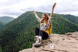 © maxbelchenko - Young woman  with backpack on mountain peak looking in beautiful mountain. Landscape with sporty young woman, green hills. Hiking. Nature. Travel and tourism.