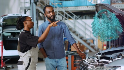 Trained serviceman in repair shop using holographic augmented reality to show woman defective components inside car. Seasoned garage professional using advanced AR software to project vehicle parts