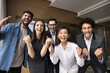 Multiethnic business team of excited project colleagues celebrating teamwork success, successful startup, making winning fist hand gestures, laughing, shouting for joy at camera