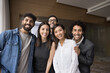 © fizkes - Cheerful multiethnic team of office friends standing close together, hugging looking at camera, smiling, laughing. Successful business colleagues posing for portrait, enjoying corporate friendship