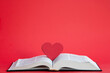 Red heart on an open book with a red background