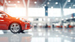 A red new car on display in a modern, brightly lit car dealership showroom, focus on vehicle with blurred surroundings.