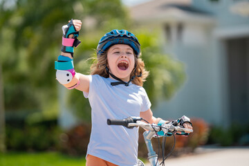 Wall Mural - Kids first bike. Child learning to ride bike. Kid riding bike in a helmet. Child with a childs bike and in protective helmet. Articles on safety and summer activity. Happy kid boy having fun in park.