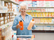 © StockPhotoPro - Senior customer comparing products at the supermarket