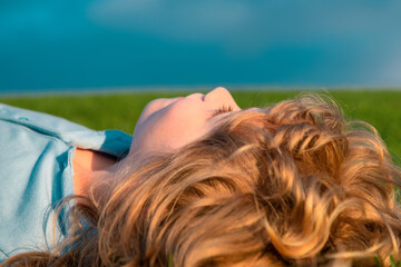 Sticker - Happy child enjoying on grass field and dreaming. Kid relax on nature. Summer dream. Kid dreams on grass. Childhood dream. Daydreamer child. Dreams and imagination. Dreamy kids face.