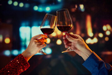 Wall Mural - Valentine's Day special promotion at a boutique hotel. Male and female hands clinking glasses with red wine. Anniversary celebration. Romance, Concept of holidays, celebration, events