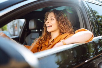 A happy woman is driving a car and smiling. Automobile travel. Sharing a car. Lifestyle concept.